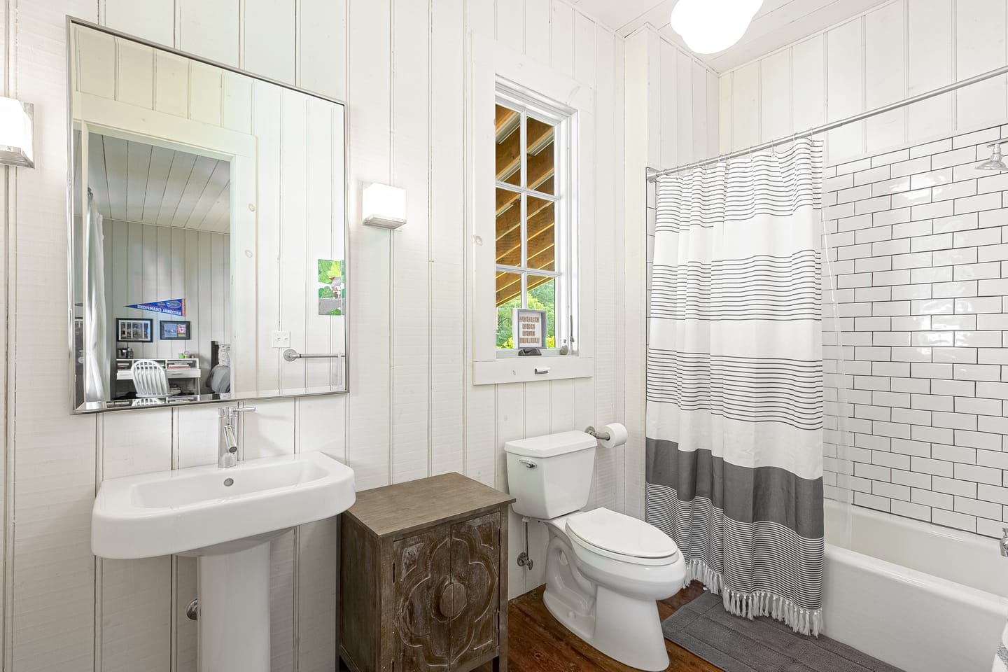 Bathroom with shiplap walls, a pedestal sink and a tub with shower