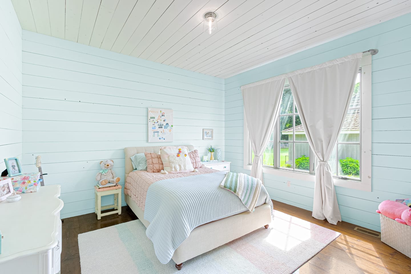 Bedroom with pale blue shiplap walls and tall windows