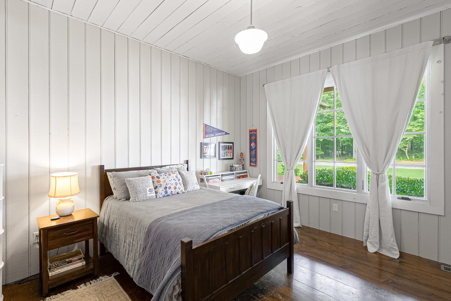 Bedroom with vertical shiplap walls and a schoolhouse pendant light