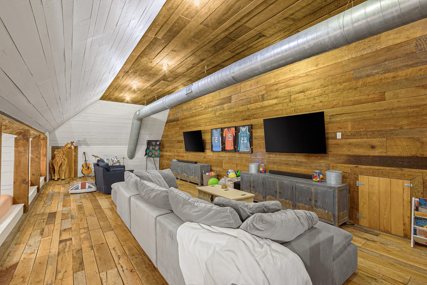 Upstairs bonus room with a reclaimed wood wall and exposed ductwork