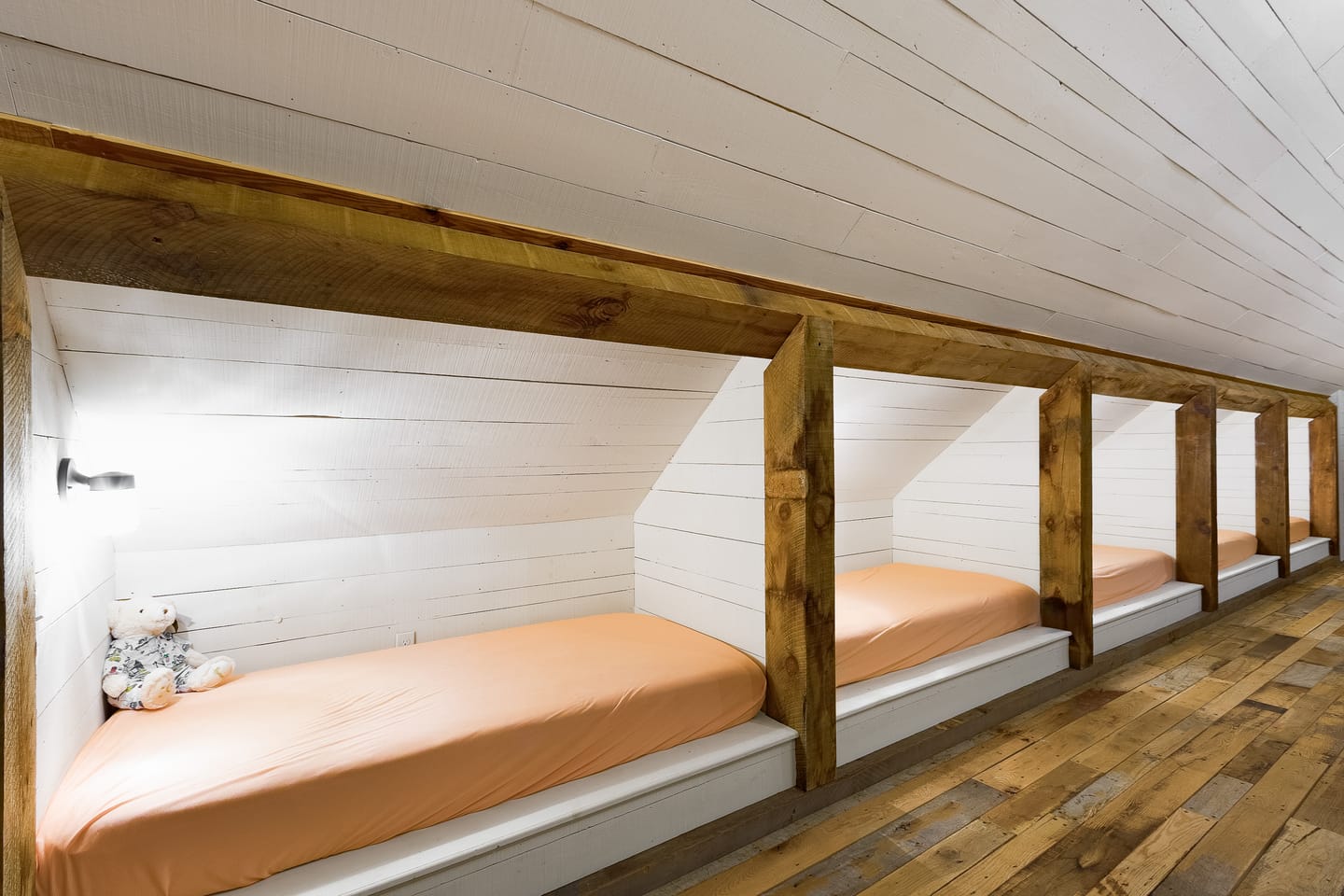 Row of built-in bed nooks framed in reclaimed wood