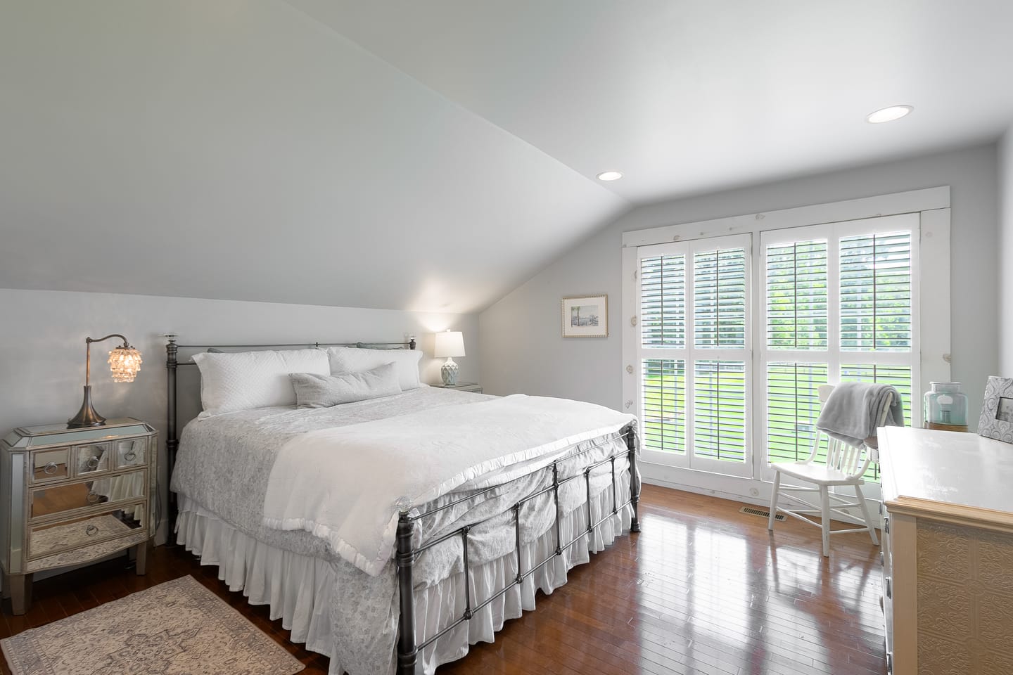 Carriage house bedroom with an iron bed and shuttered windows