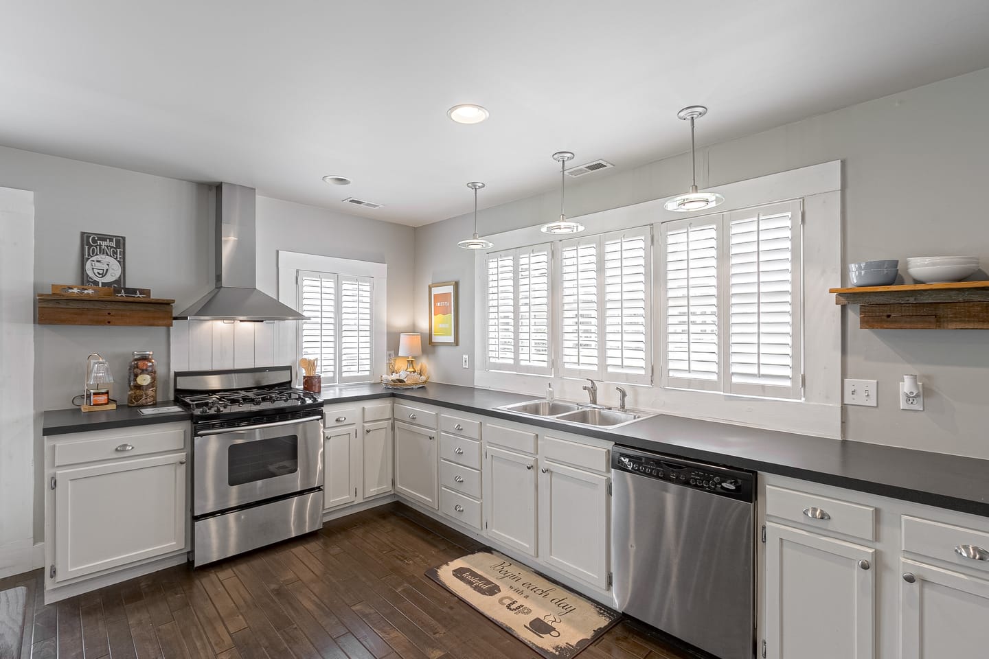 Carriage house kitchen with white cabinetry, a stainless gas range and plantation shutters