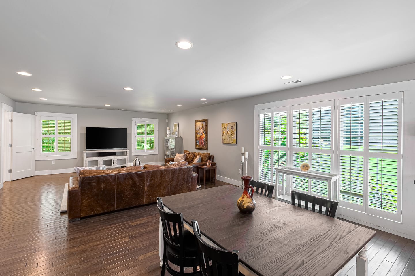 Carriage house living and dining room with plantation shutters and wood floors