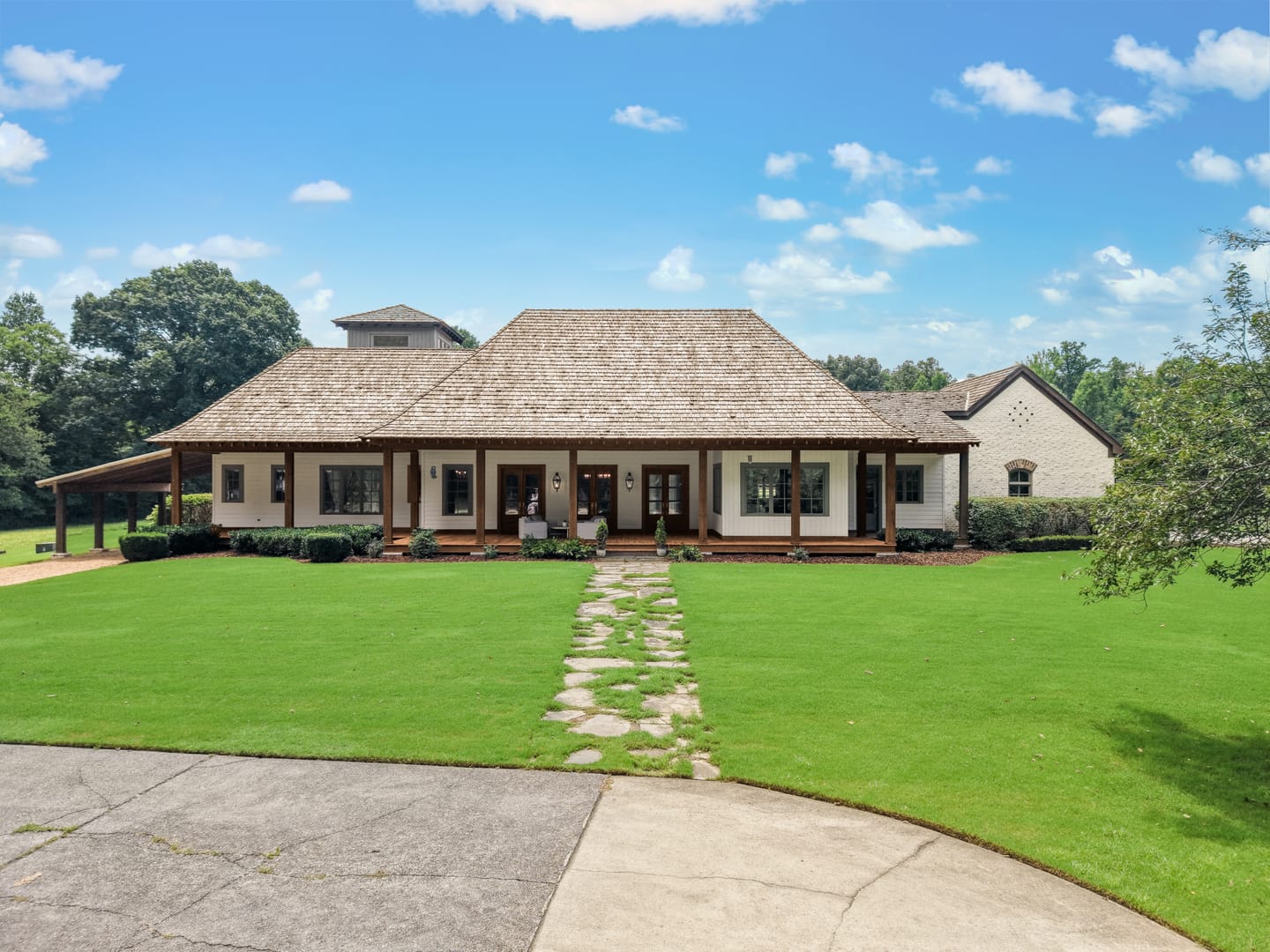 Main residence with a long covered front porch and a stone path across the front lawn