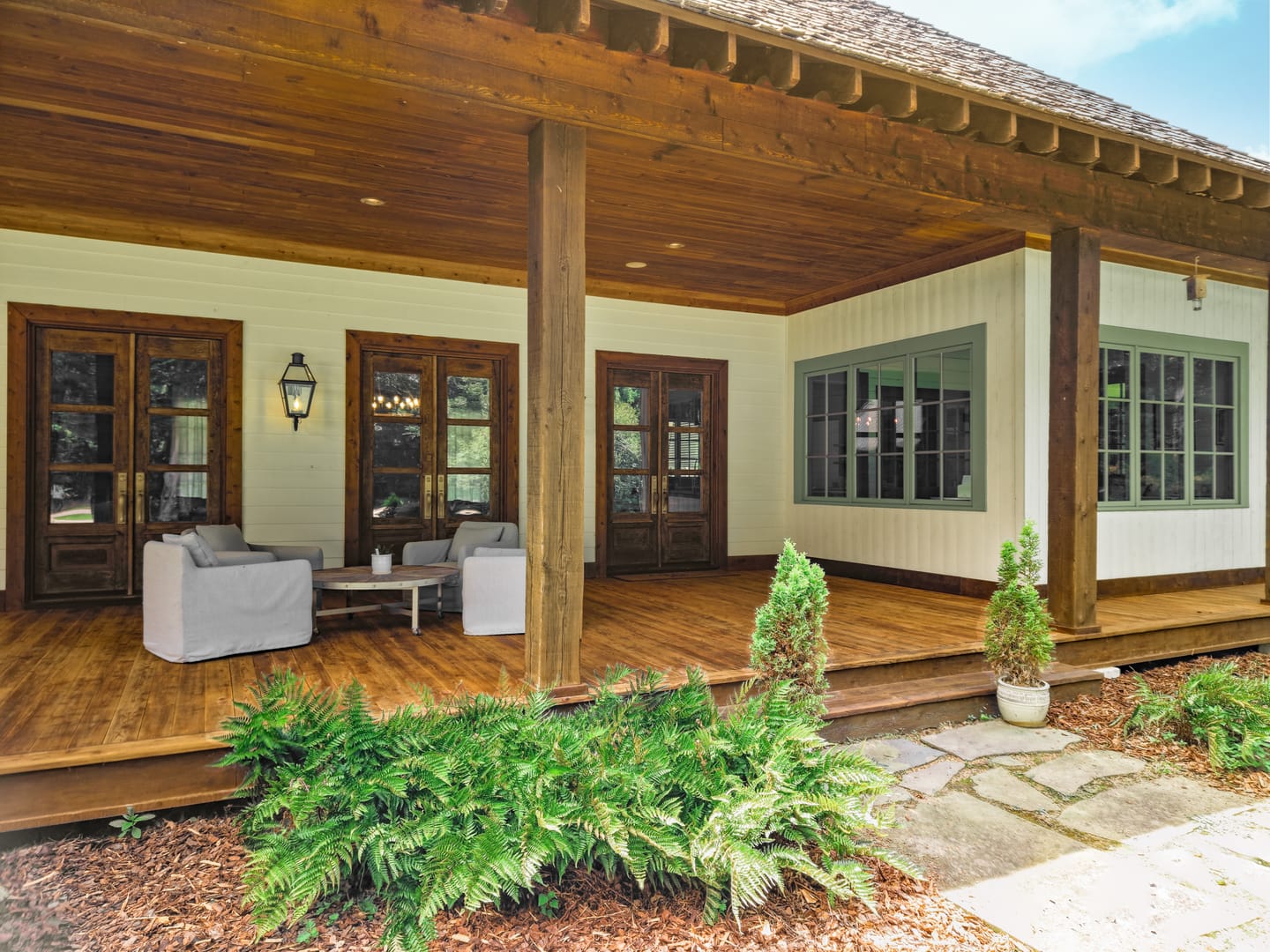 Covered front porch with seating, a wood ceiling and French doors