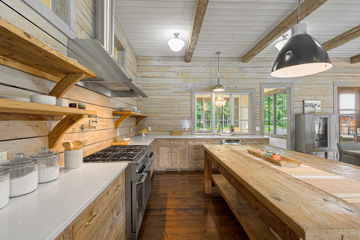 Kitchen with a long reclaimed wood island, open shelving, a range hood and a professional gas range