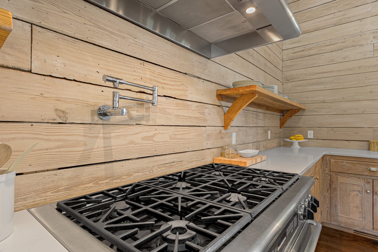 Professional gas range with a pot filler against a backsplash of wide reclaimed planks