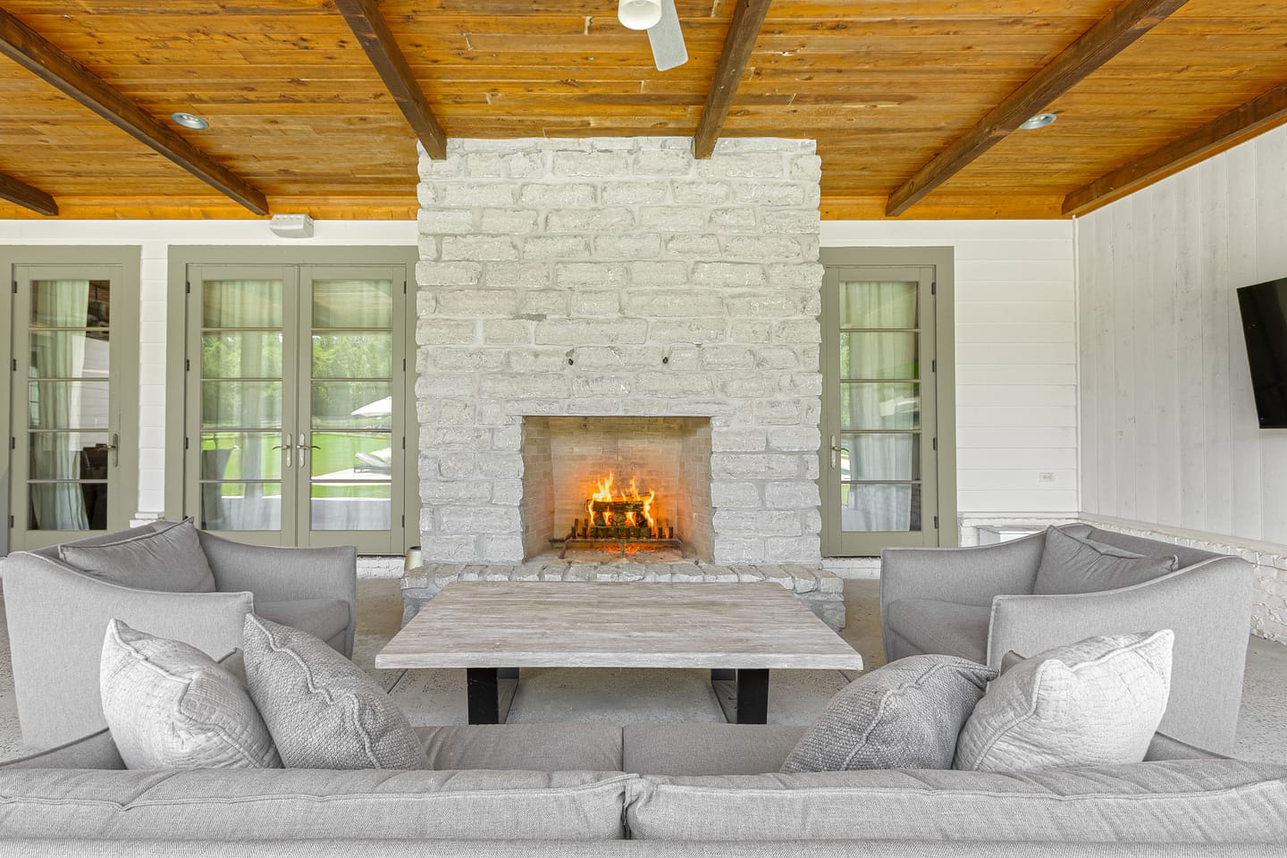 Wood-burning stone fireplace in the covered outdoor living room