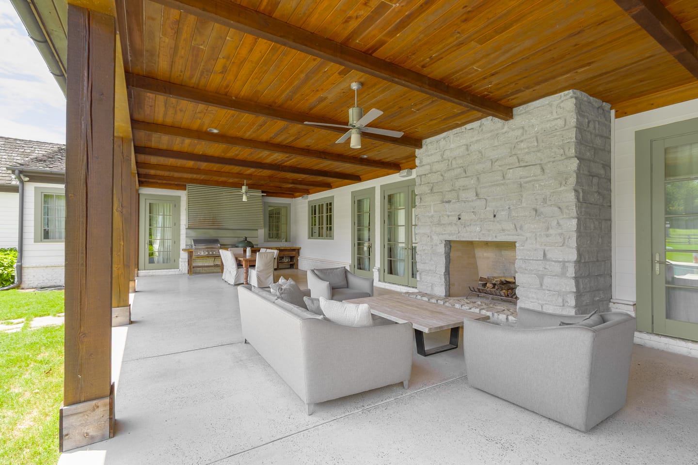 Covered outdoor living room with a stone fireplace and an outdoor kitchen