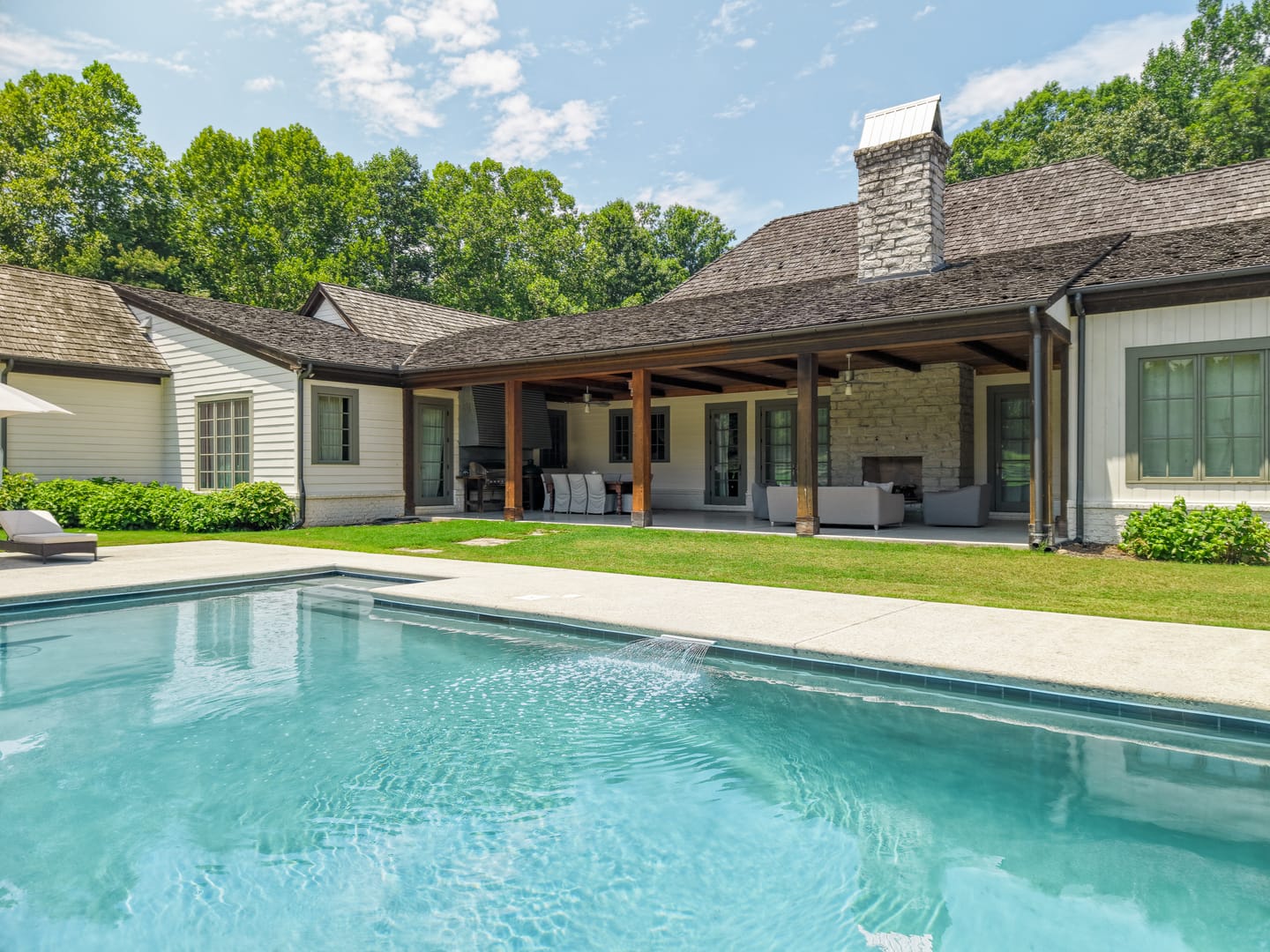 Pool and the back of the main residence with its covered porch and stone chimney
