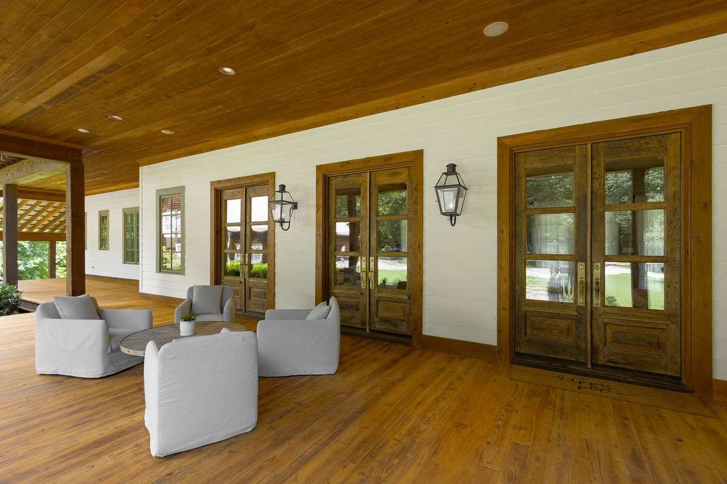 Covered porch seating beside French doors and lantern sconces