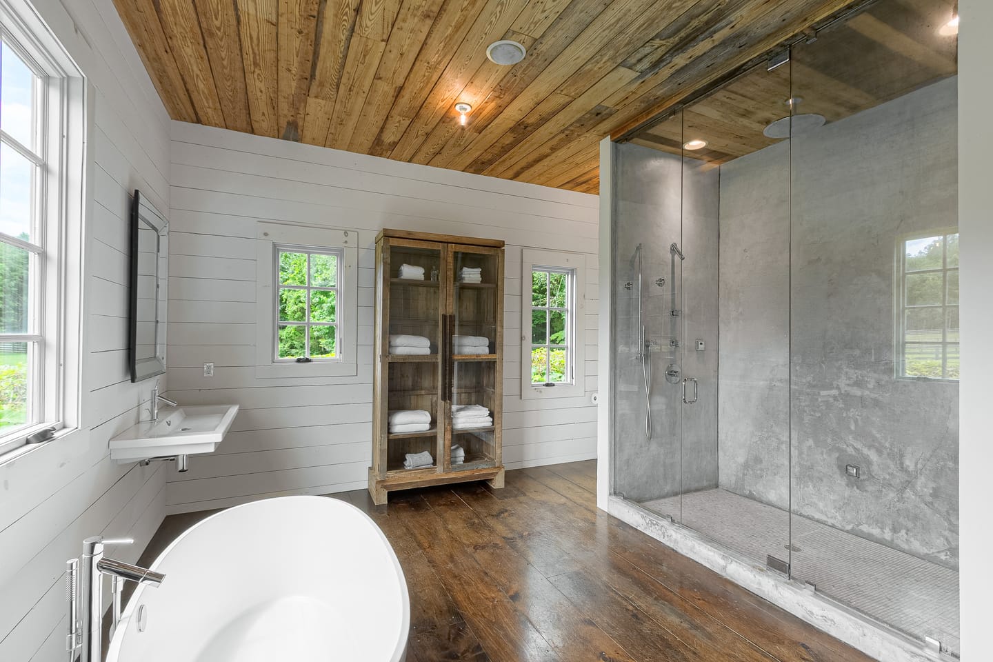 Primary bath with a glass-enclosed walk-in shower and a glass-front linen cabinet