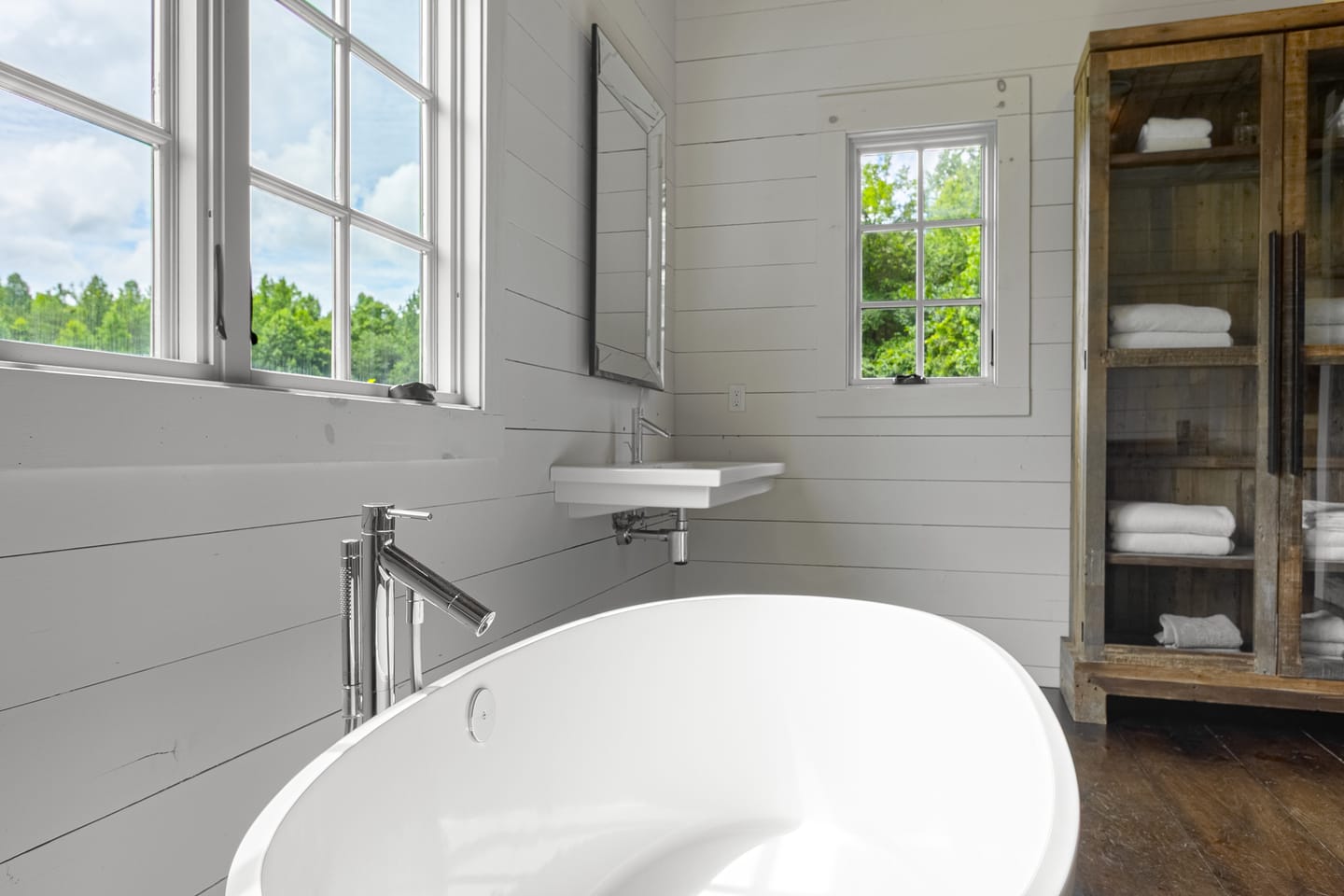 Freestanding tub beneath windows looking out to the trees