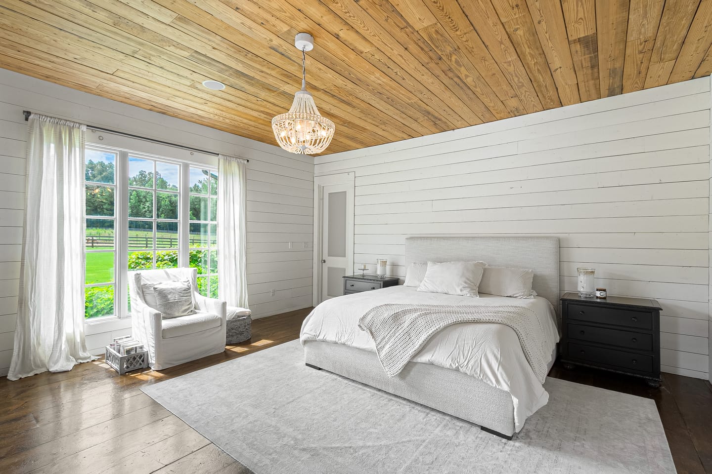 Primary bedroom with a wood plank ceiling, beaded chandelier and pasture views