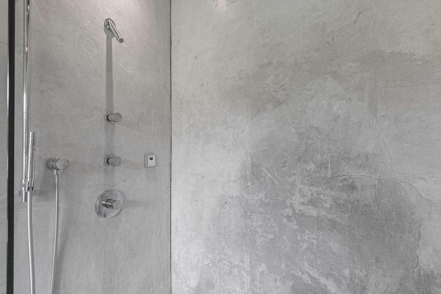 Walk-in shower with smooth grey walls and brushed fixtures