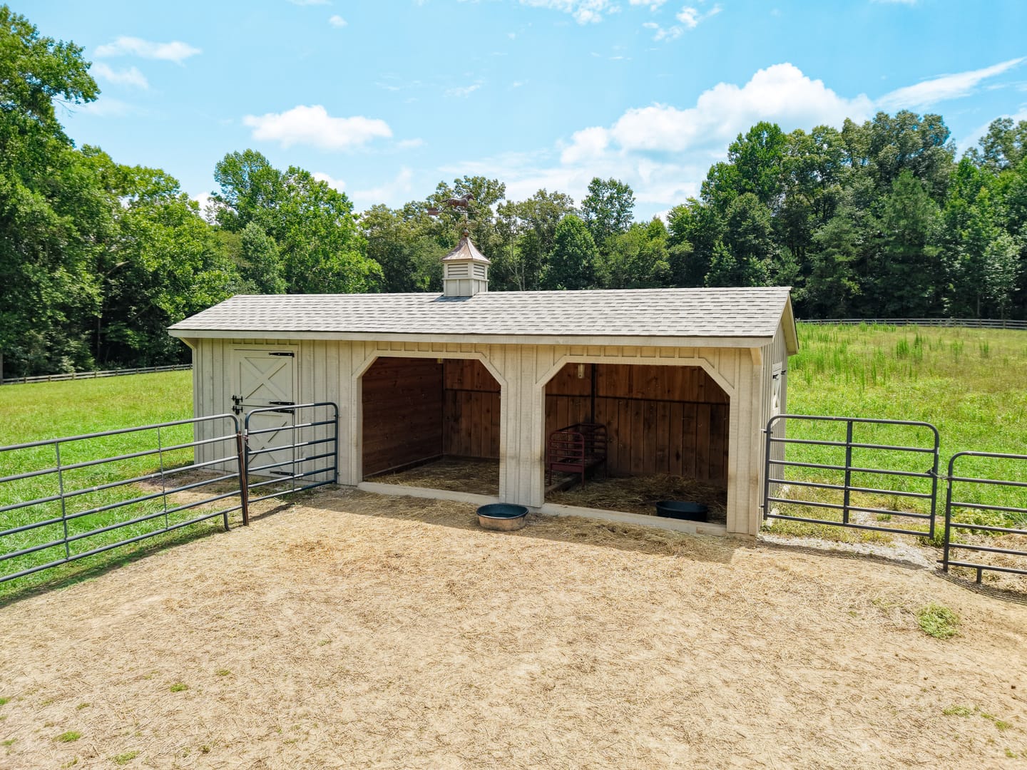 Run-in shed with two open stalls and a pipe-fenced paddock