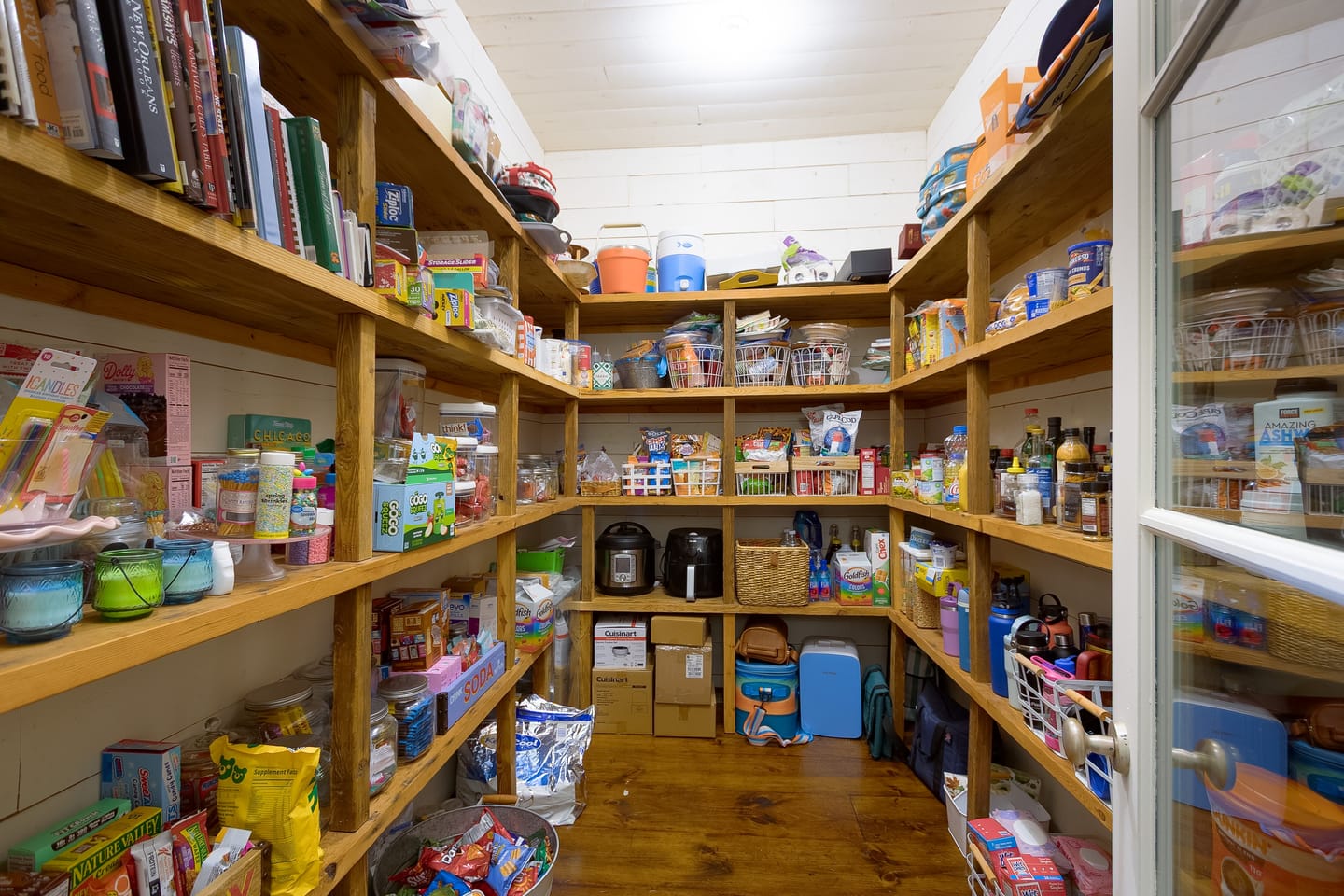 Walk-in pantry lined with floor-to-ceiling wood shelving